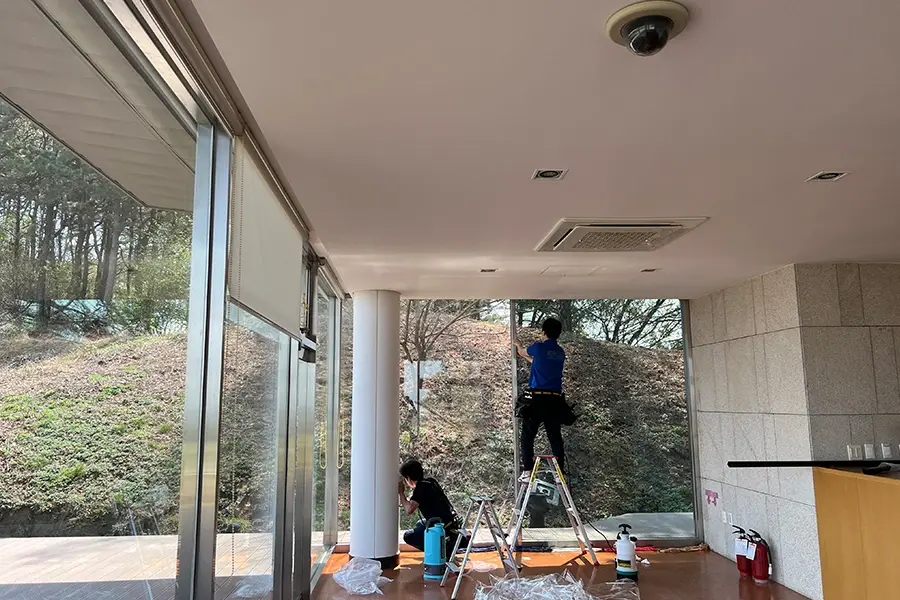 사다리 위에서 진행 중인 창문단열필름 시공 작업 모습